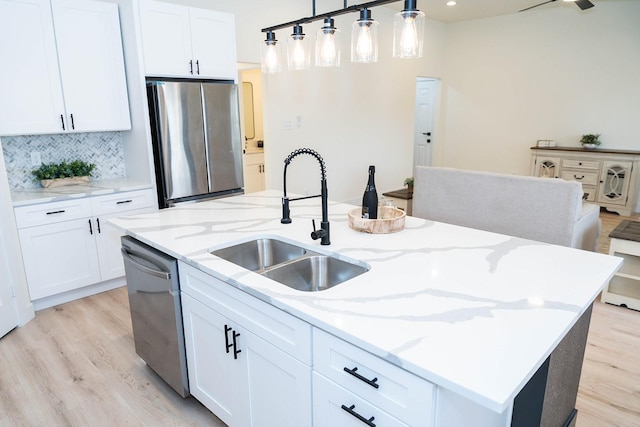 kitchen featuring pendant lighting, white cabinetry, sink, a kitchen island with sink, and stainless steel appliances