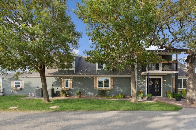 view of front facade with a balcony, cooling unit, and a front lawn