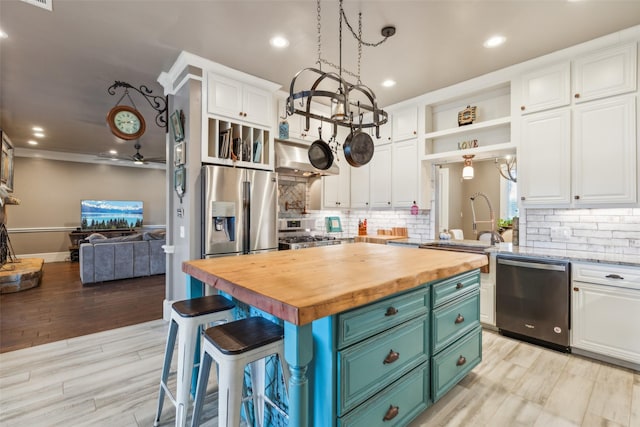 kitchen featuring stainless steel appliances, white cabinets, a center island, and butcher block counters