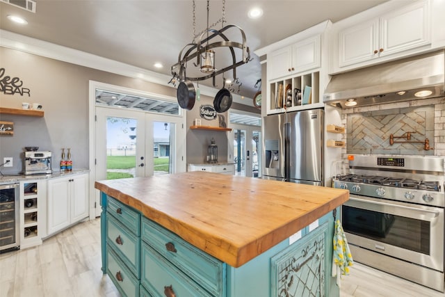 kitchen featuring a center island, wooden counters, crown molding, white cabinets, and appliances with stainless steel finishes