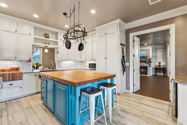 kitchen with butcher block counters, white cabinets, blue cabinetry, and a kitchen breakfast bar