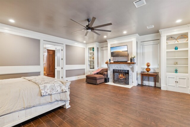 bedroom with a high end fireplace, ceiling fan, and dark hardwood / wood-style floors