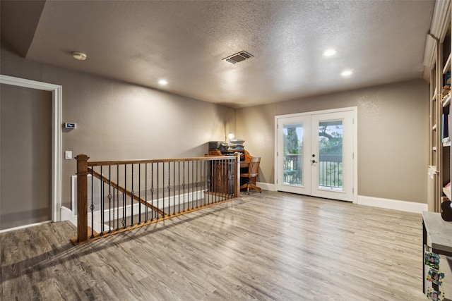 empty room with a textured ceiling, french doors, and wood-type flooring