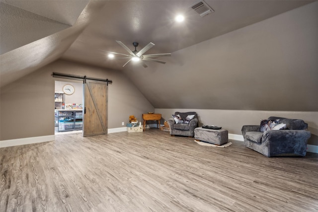 bonus room featuring ceiling fan, a barn door, lofted ceiling, and hardwood / wood-style flooring