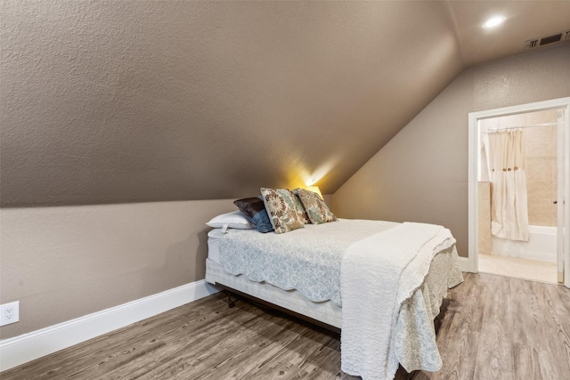 bedroom featuring lofted ceiling, wood-type flooring, and connected bathroom