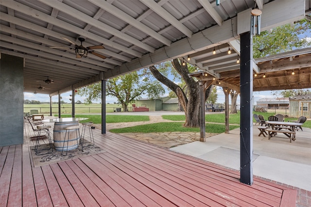 wooden terrace featuring ceiling fan, a yard, and a patio