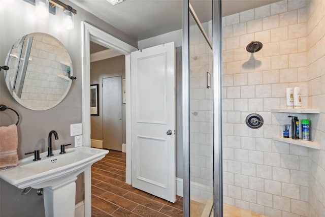 bathroom featuring a shower with shower door and sink