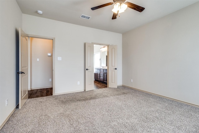 unfurnished bedroom with ceiling fan, ensuite bath, and carpet