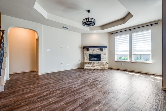 unfurnished living room with a fireplace and a tray ceiling