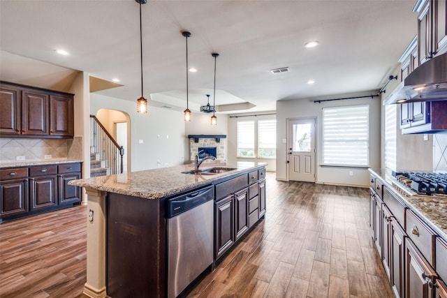 kitchen featuring appliances with stainless steel finishes, pendant lighting, a kitchen island with sink, and dark brown cabinetry