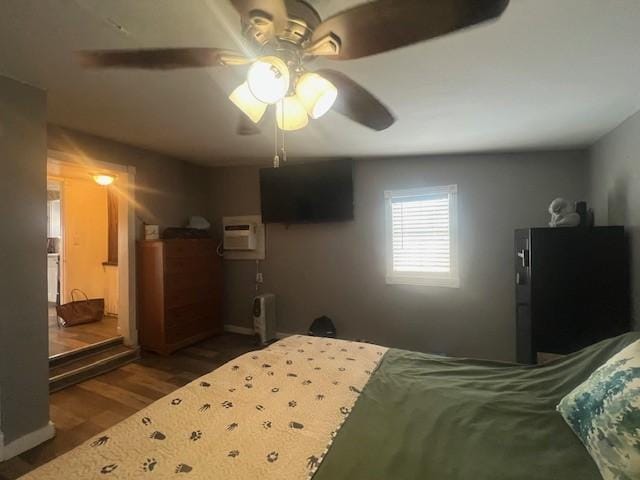 bedroom with ceiling fan, a wall unit AC, and wood-type flooring