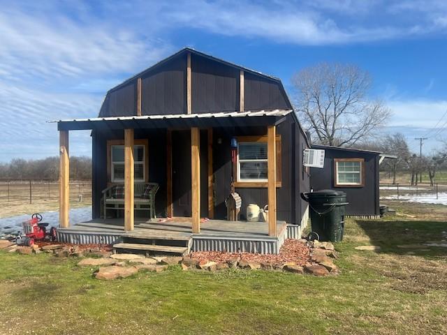 rear view of property with a wall unit AC and a lawn