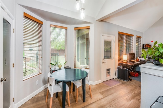 dining room with light hardwood / wood-style floors, a healthy amount of sunlight, and vaulted ceiling