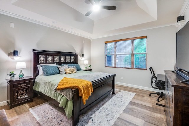 bedroom featuring ornamental molding, light wood-type flooring, ceiling fan, and a raised ceiling