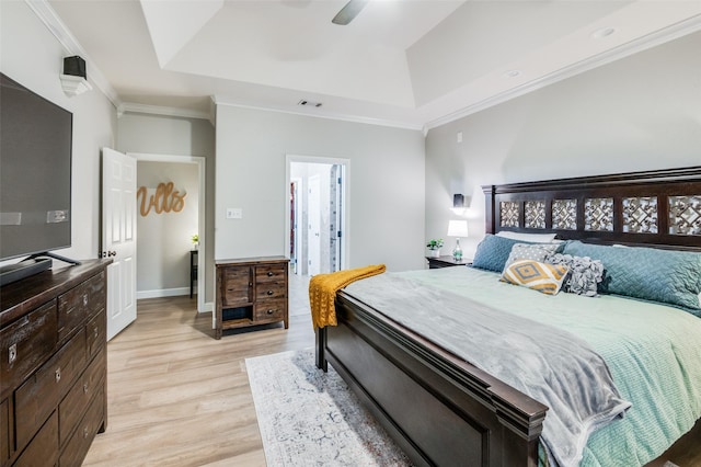 bedroom featuring ceiling fan, light wood-type flooring, a tray ceiling, and crown molding