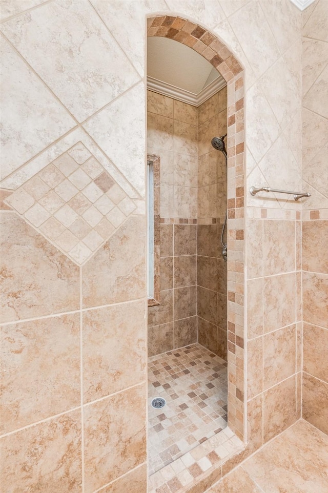 bathroom with crown molding and tiled shower