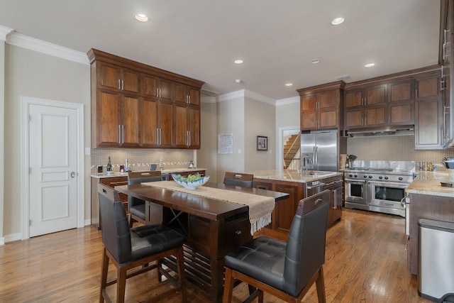 kitchen featuring stainless steel appliances, a center island, light stone countertops, and decorative backsplash