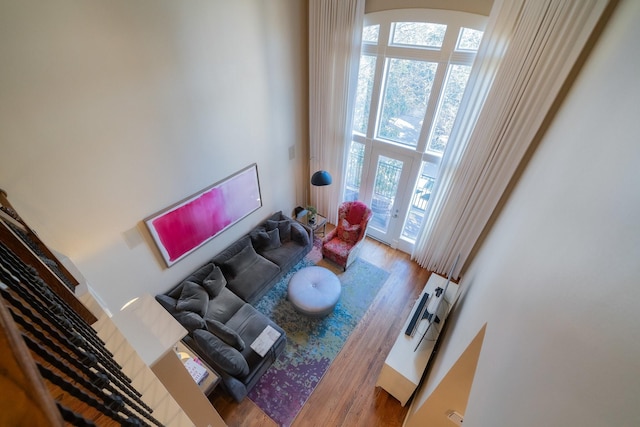 living room with hardwood / wood-style flooring and a towering ceiling