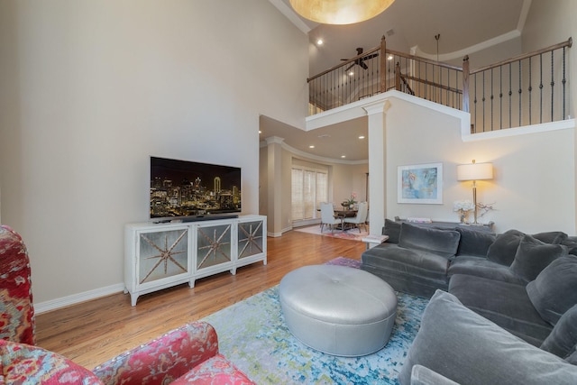 living room featuring hardwood / wood-style flooring, a high ceiling, ornamental molding, and ceiling fan