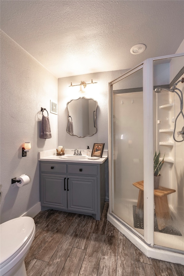 bathroom with toilet, walk in shower, vanity, hardwood / wood-style flooring, and a textured ceiling