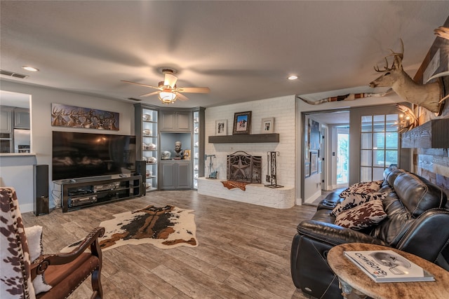 living room with ceiling fan, a fireplace, and wood-type flooring