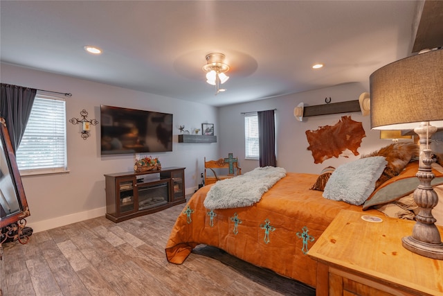 bedroom featuring ceiling fan, multiple windows, and hardwood / wood-style flooring