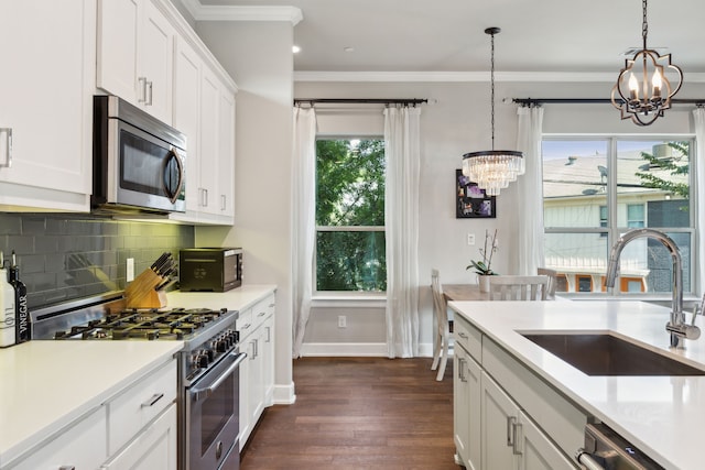 kitchen with stainless steel appliances, sink, white cabinetry, a chandelier, and pendant lighting