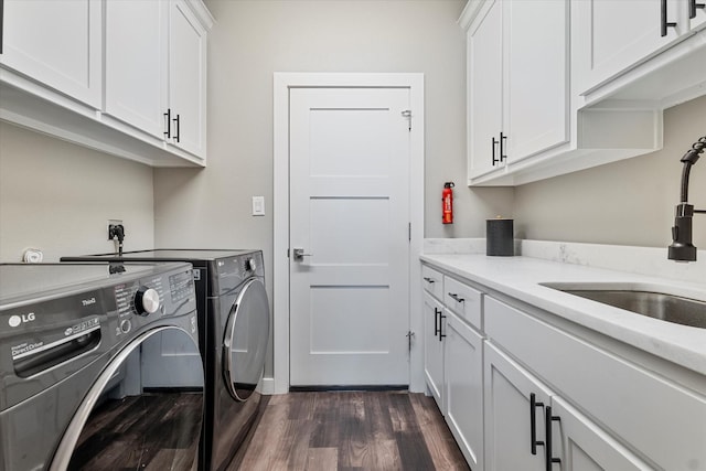 laundry area featuring sink, washing machine and clothes dryer, cabinets, and dark wood-type flooring