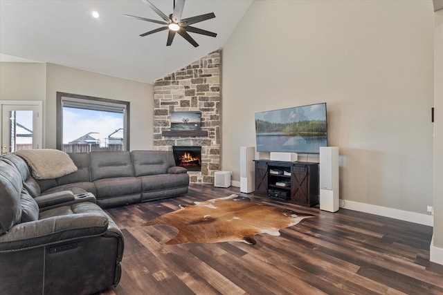 living room featuring dark wood-type flooring, high vaulted ceiling, ceiling fan, and a stone fireplace