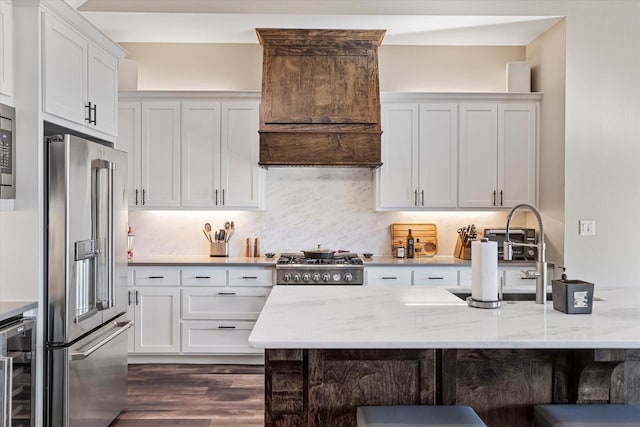 kitchen featuring stainless steel appliances, white cabinetry, light stone counters, and wine cooler