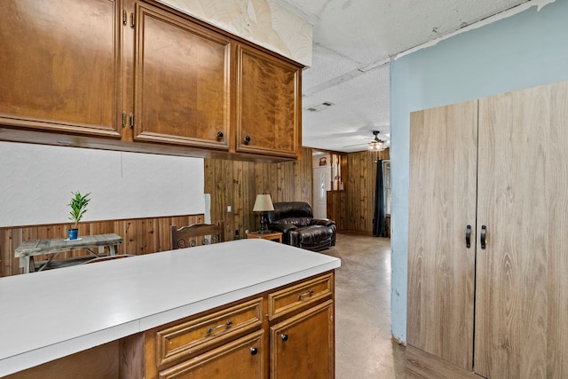 kitchen with ceiling fan and wood walls