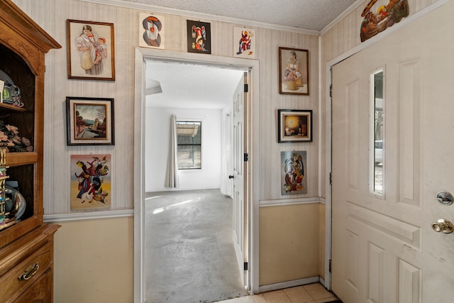 corridor with a textured ceiling, ornamental molding, and light tile patterned floors