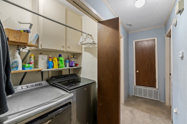 washroom featuring a textured ceiling, cabinets, ornamental molding, and washing machine and clothes dryer