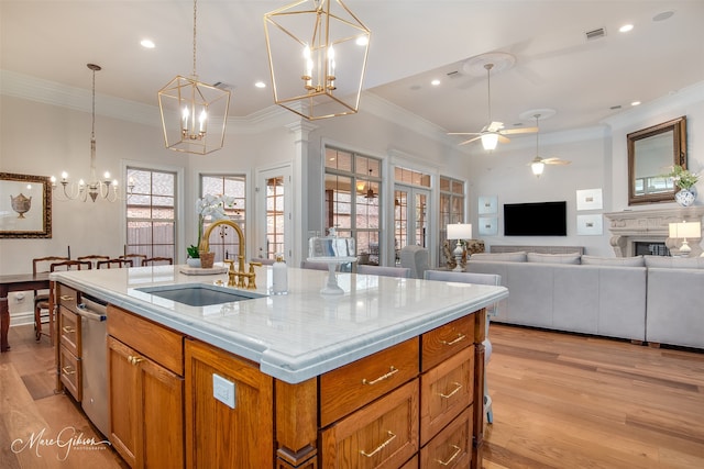 kitchen with a center island with sink, ceiling fan, pendant lighting, light hardwood / wood-style flooring, and sink