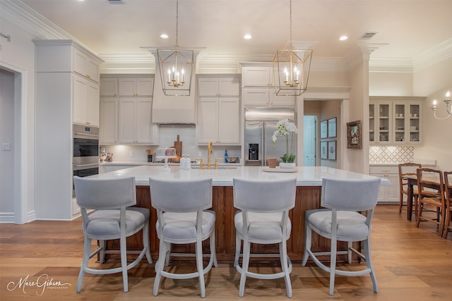 kitchen featuring light hardwood / wood-style floors, stainless steel built in refrigerator, a large island, and tasteful backsplash