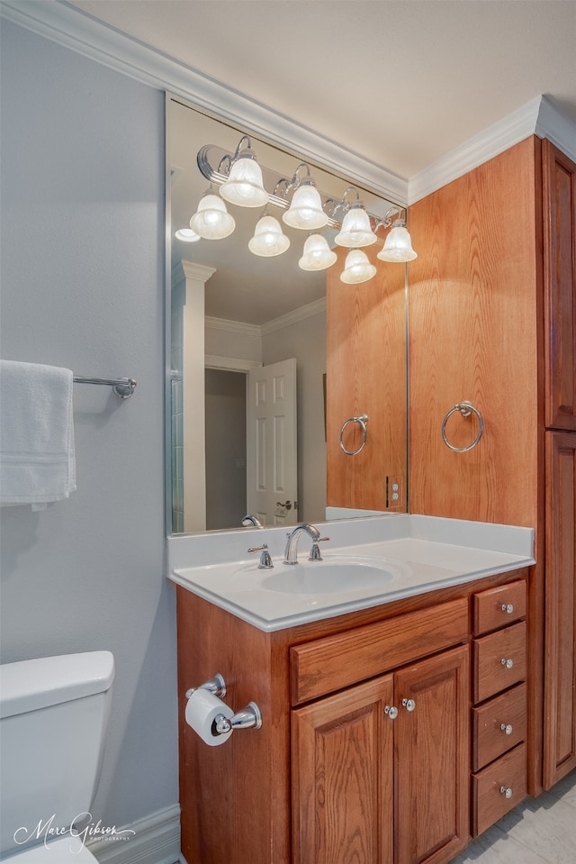 bathroom with toilet, vanity, and crown molding