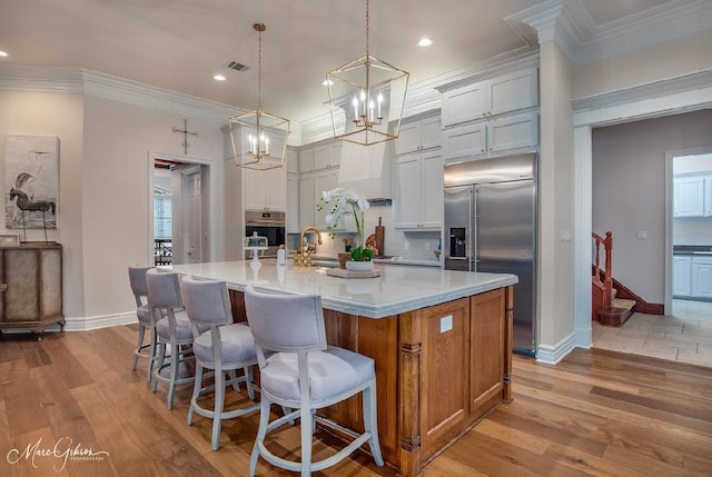 kitchen with crown molding, appliances with stainless steel finishes, pendant lighting, and a large island