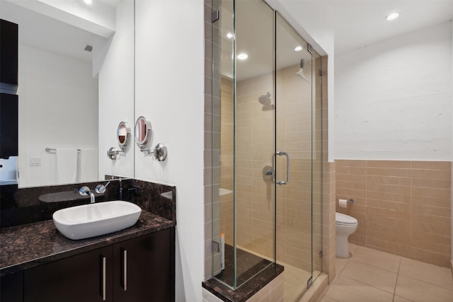 bathroom with toilet, tile walls, tile patterned floors, a shower with shower door, and vanity