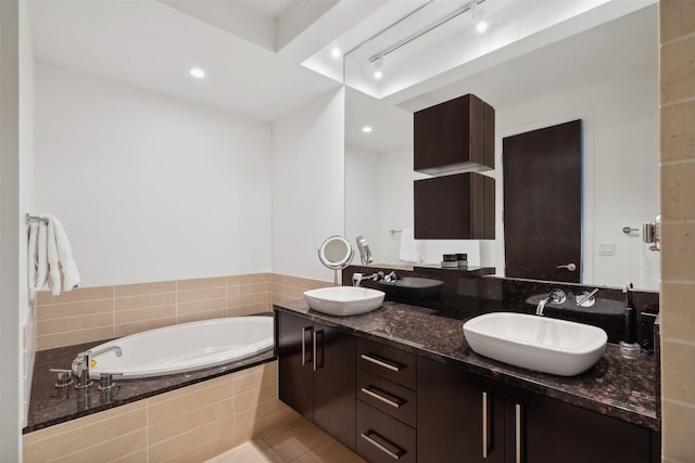 bathroom featuring a relaxing tiled tub, tile patterned flooring, and vanity