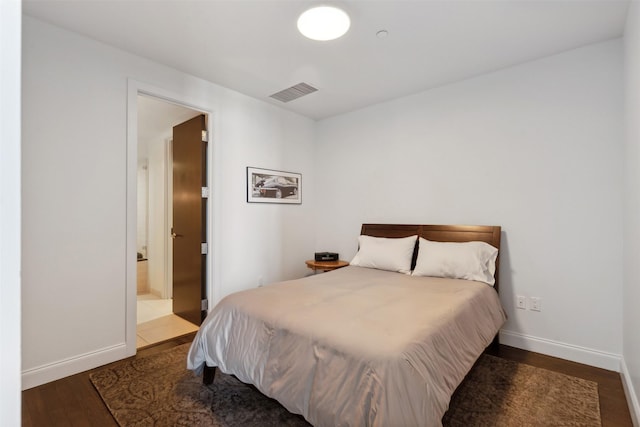 bedroom with ensuite bathroom and dark hardwood / wood-style floors