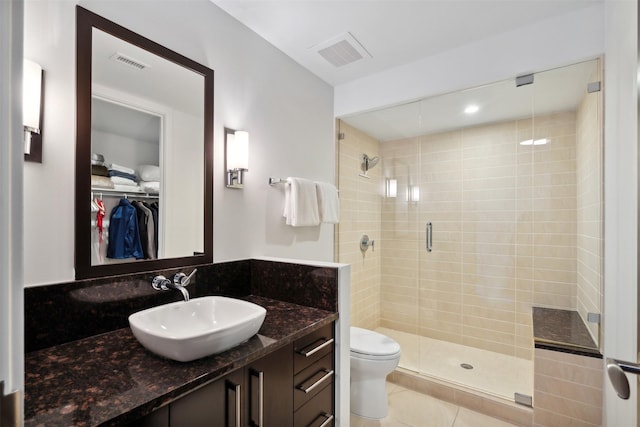 bathroom featuring toilet, tile patterned flooring, vanity, and a shower with shower door