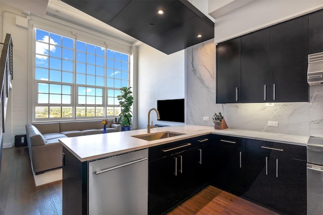 kitchen featuring sink, dishwasher, kitchen peninsula, decorative backsplash, and dark hardwood / wood-style floors