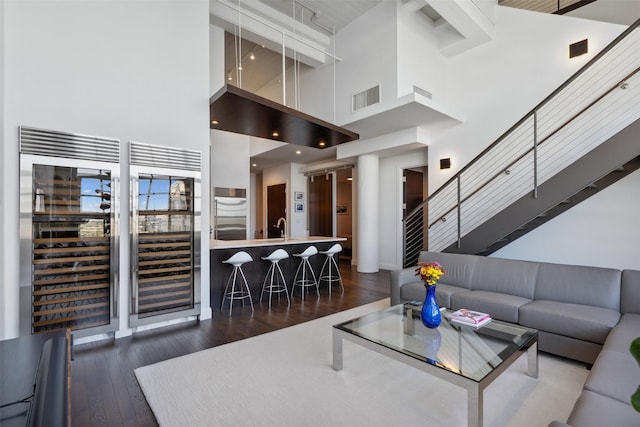 living room with a high ceiling, dark hardwood / wood-style flooring, beverage cooler, and sink