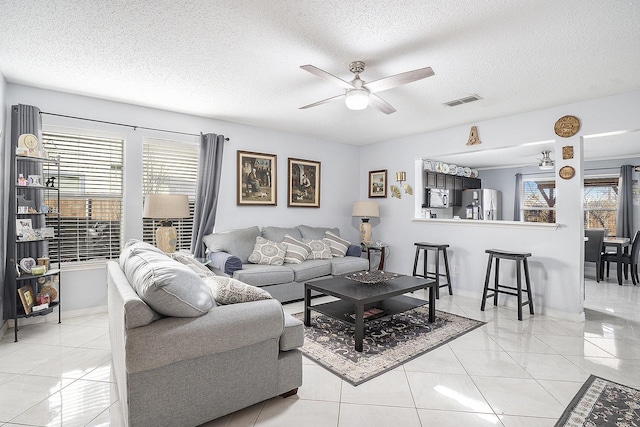 living room with light tile patterned floors, a textured ceiling, ceiling fan, and plenty of natural light