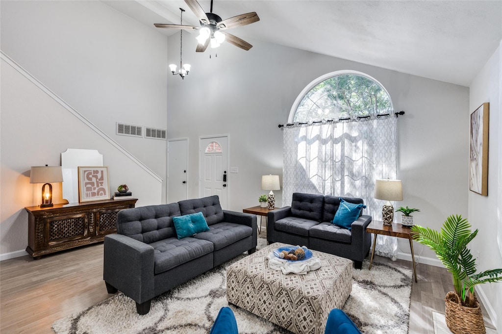 living room featuring light wood-type flooring, high vaulted ceiling, and ceiling fan with notable chandelier