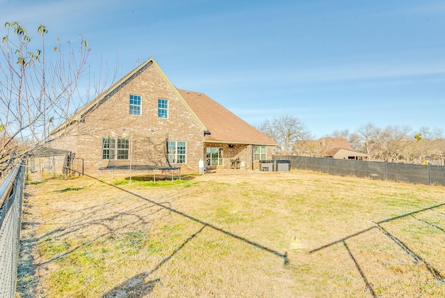 rear view of house with a yard and a trampoline