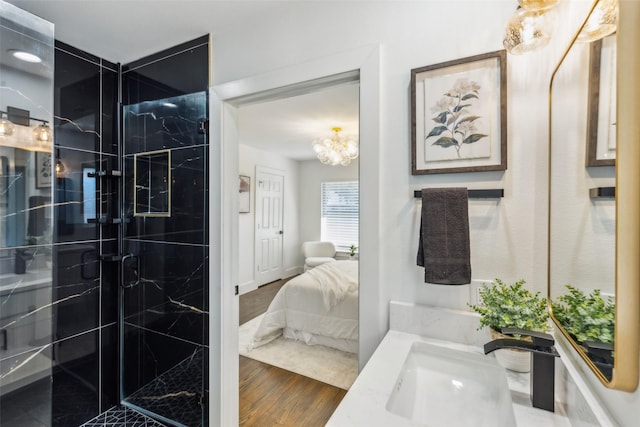 bathroom featuring wood-type flooring, a shower with door, an inviting chandelier, and vanity