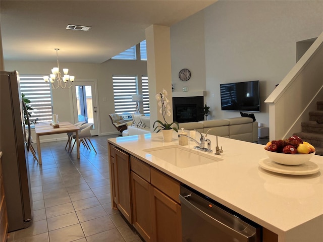 kitchen with sink, decorative light fixtures, light tile patterned floors, an island with sink, and appliances with stainless steel finishes