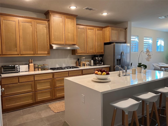 kitchen featuring a kitchen breakfast bar, stainless steel appliances, an island with sink, tile patterned floors, and sink