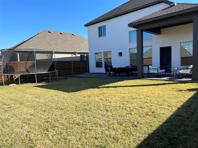 rear view of house featuring a yard, a trampoline, and a patio